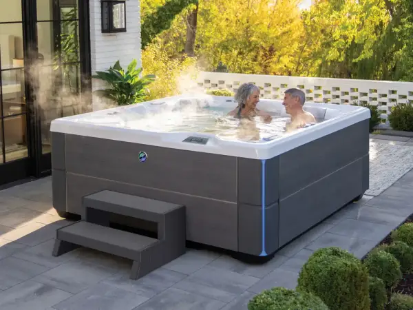 Para relaksu w ogrodzie: para cieszy się gorącą kąpielą w nowoczesnych wannach spa ogrodowych, otoczonych zielenią i słońcem.
