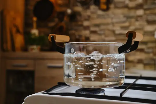Comment avoir de l'eau chaude sans chauffe eau : une casserole en verre bout sur une cuisinière à gaz.