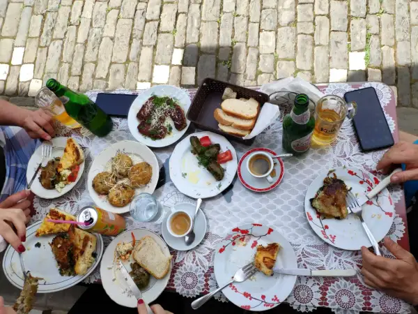 Pyszne albania jedzenie: mięso, gołąbki, placki i pieczywo na stole, obok piwo i kawa.