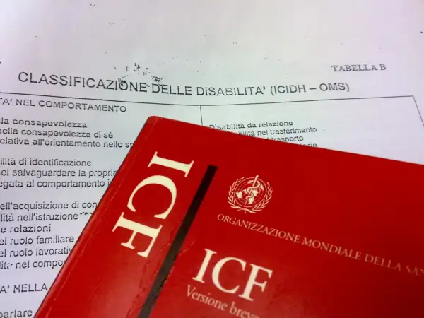 Classificazione delle disabilità (ICIDH - OMS) e copertina rossa del manuale ICF.