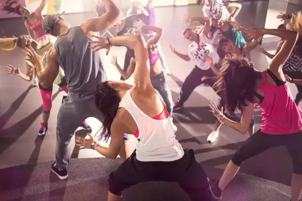 Un gruppo di persone balla con energia durante una lezione di Zumba. Movimento e divertimento per chi vuole che zumba fa dimagrire.