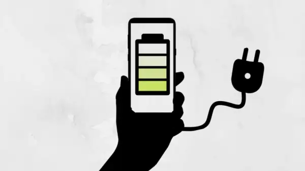 Mano sosteniendo un teléfono con batería a 3/4, conectado a un enchufe. ¡Un truco para el ahorro de batería!