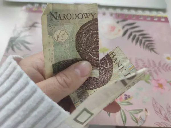 Dłoń trzyma sklejony banknot 10 zł. Zastanawiasz się, co zrobić ze sklejonym banknotem?