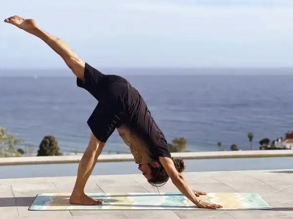 Hombre en postura de perro boca abajo, practicando yoga flow que es una secuencia fluida de posturas.