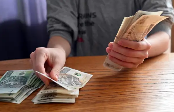 Dłonie liczą polskie banknoty. Zastanawiasz się, jakie dane o użytkownikach zbierają aplikacje pożyczkowe pod pretekstem loterii?
