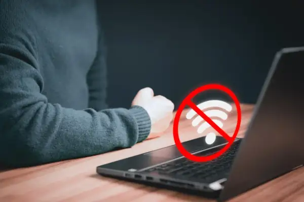 Laptop nie widzi wifi. Czerwony okrąg z przekreślonym symbolem wifi nad klawiaturą sugeruje problem z połączeniem internetowym.