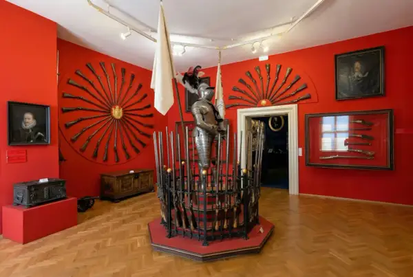 Armure de chevalier et fusils anciens exposés dans une salle rouge vif, un aperçu de l'interieur chateau de Prague.