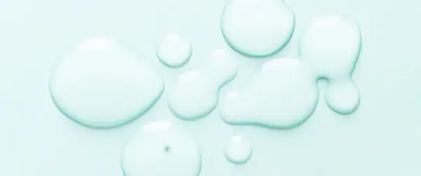 Gocce trasparenti su sfondo azzurro. Alcuni si chiedono se il cocamidopropyl betaine fa male, ma questa immagine mostra solo liquidi puri.