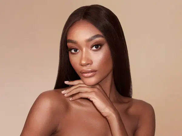 Modella con pelle scura e capelli lisci, evidenziando la differenza tra bronzer e contouring per scolpire il viso.