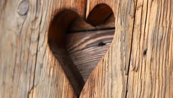 Corazón tallado en madera rústica, mostrando el encanto del envejecer madera.