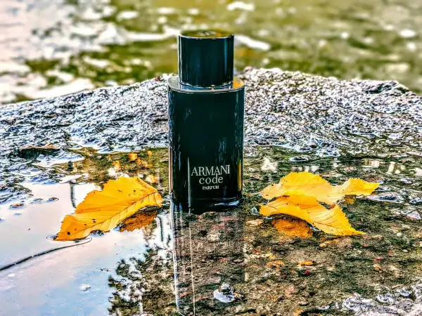 Elegancki flakon Armani Code Parfum 125ml, otoczony jesiennymi liśćmi i wodą, emanuje luksusem.