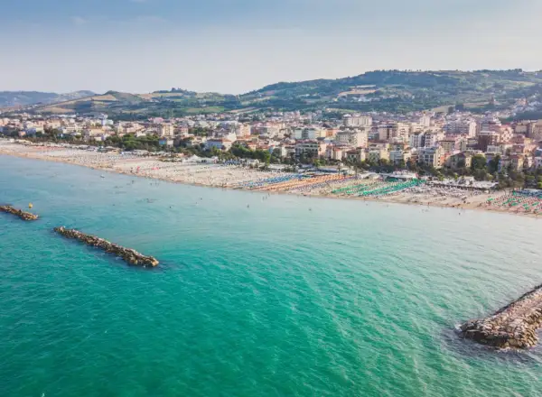 Vista aerea di San Benedetto del Tronto, con il suo lungomare affollato di ombrelloni colorati e il mare turchese.