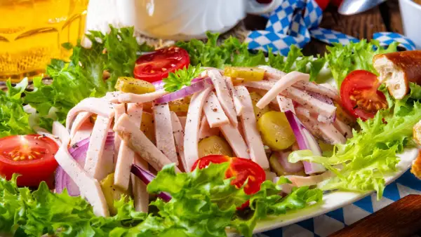 Ein leckerer Wurstsalat mit Tomaten, Gurken und Zwiebeln, perfekt für ein deftiges wurstsalat rezept. Dazu ein Glas Bier.