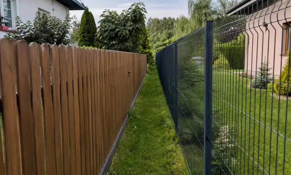 Dwa płoty, drewniany i metalowy, stoją obok siebie. Czy można postawić płot przy płocie? Tak, jak widać na zdjęciu.
