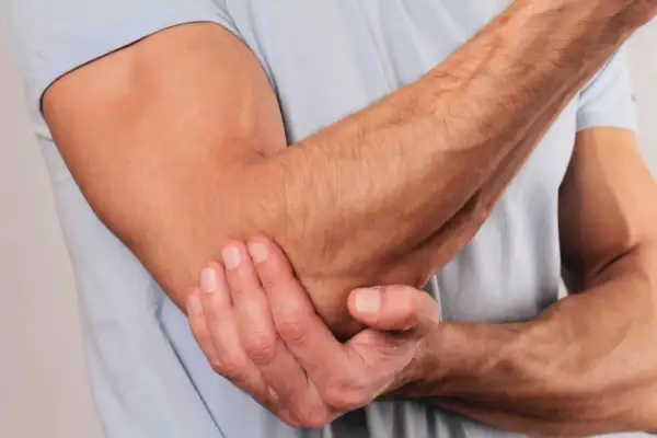 En man håller sin armbåge, som om han har ont i underarmen ovansida.