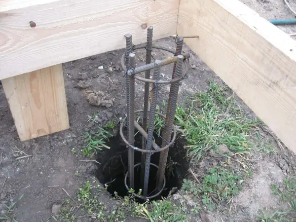 Zbrojenie słupa fundamentowego pod starym drewnianym domem. Przygotowanie do wylania betonu.