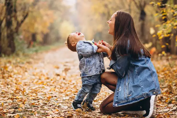 Mamma e figlio ridono felici in un bosco autunnale. Le loro risate sono come le più belle frasi madre figlio.