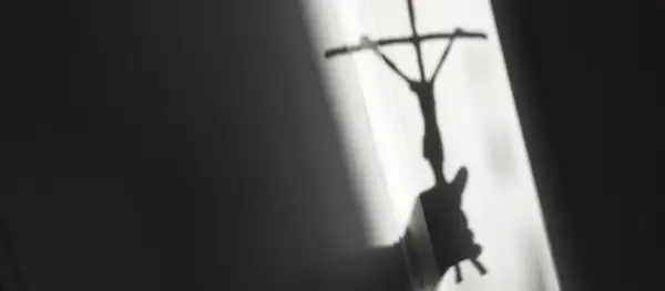 Schatten eines Kreuzes mit Jesusfigur, der eine kritische Auseinandersetzung mit evangelischen Freikirchen andeutet.