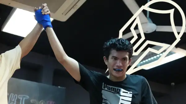 A boxer's corner man raises his hand in victory, celebrating a hard-fought win.
