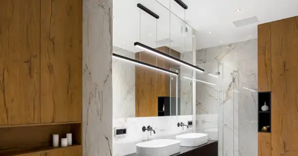 Bagno moderno con lavabi bianchi, specchio ampio e moderne idee illuminazione bagno con lampade a sospensione nere.