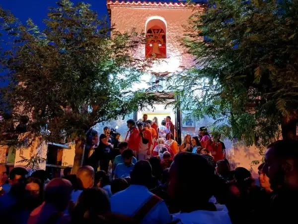 Multitud reunida frente a una iglesia iluminada, disfrutando de las fiestas de Calatayud.
