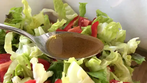 Löffel mit balsamico dressing über frischem Salat mit Tomaten und Paprika.