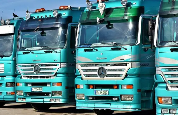 Varios camiones Mercedes-Benz Actros turquesas en fila. ¿Cuántos litros de aceite lleva un camión? Depende del modelo, pero estos gigantes pueden necesitar entre 20 y 40 litros.