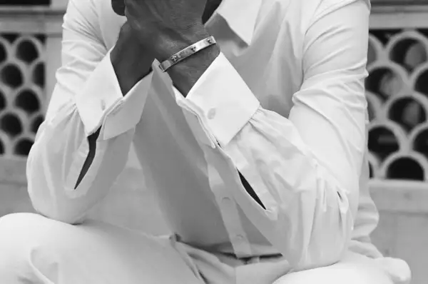 Un homme porte une chemise manchette homme blanche, ornée d'un bracelet argenté.
