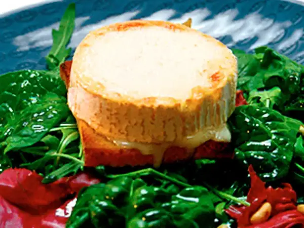 Varm chevre chaud på rostat bröd, serverad med en fräsch sallad av spenat och ruccola. Smältande ost och gröna blad.