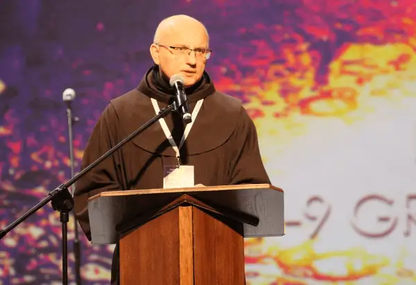 Ksiądz w habicie przemawia przy mównicy. Jego opinia kościoła jest ważna dla zgromadzonych.