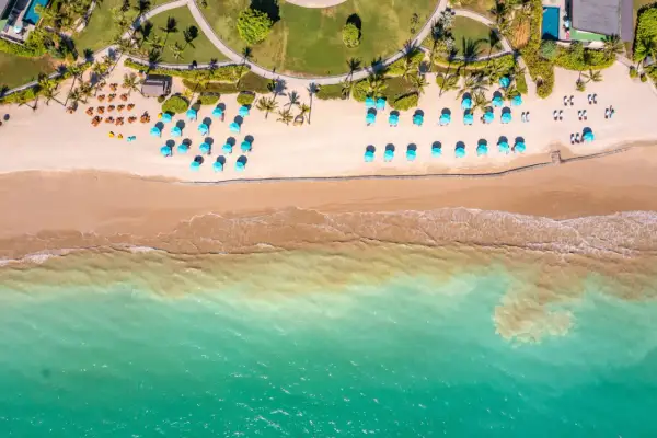 En vacker strand i Khao Lak med turkosa paraplyer och solstolar på sanden. Vågor sköljer in mot stranden.