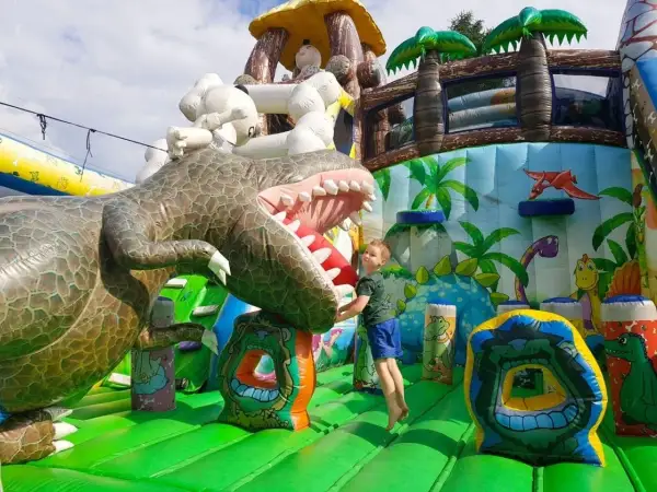 Chłopiec skacze na dmuchanym dinozaurze. Wspaniałe, ciekawe miejsca do 100 km od Katowic dla dzieci.