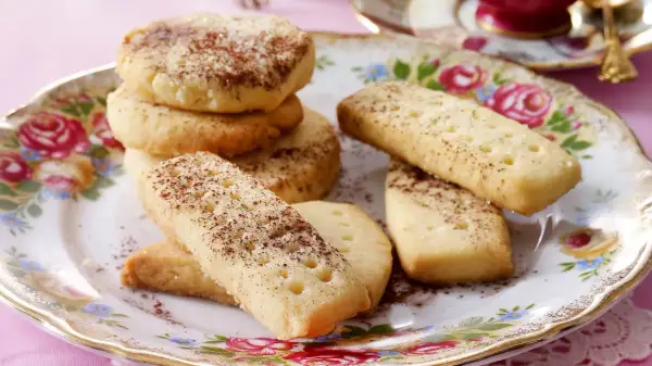 Leckeres Shortbread-Rezept: goldbraune Kekse, rund und rechteckig, mit Zimt und Zucker bestreut, auf einem floralen Teller.