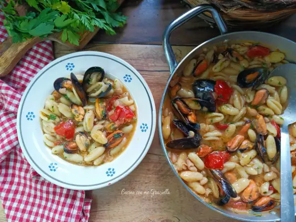 Un piatto invitante di cavatelli cozze e fagioli, con pomodorini e prezzemolo fresco. Un sapore di mare e terra.