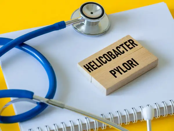 Stetoskop i klocki z napisem "Helicobacter pylori" symbolizują problemy zdrowotne, w tym potencjalne helicobacter pylori objawy psychiczne.