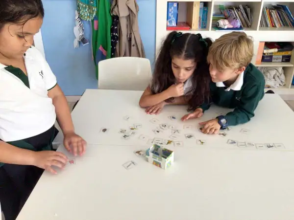 Niños concentrados en juegos de verbos con tarjetas de imágenes.