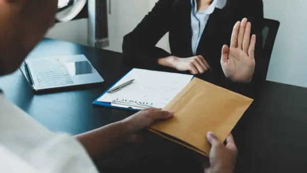 Une main tend une enveloppe, l'autre la refuse. Une scène évoquant le délai réponse inspection du travail licenciement salarié protégé.