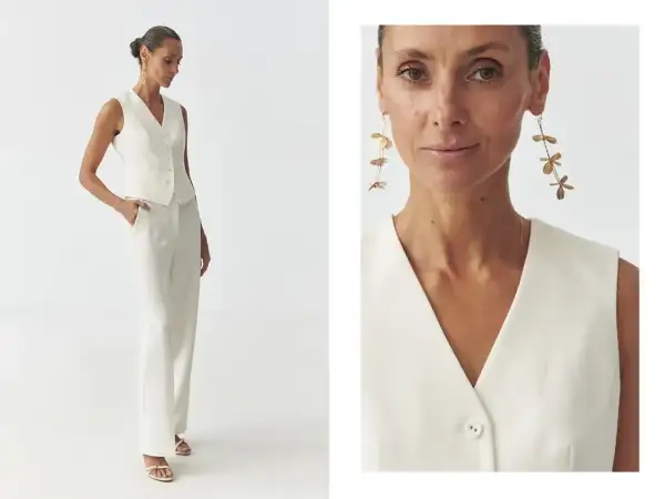 Elegancka biała kamizelka i spodnie tworzą stylowy komplet. Długie, złote kolczyki dodają szyku. Biała kamizelka stylizacje na co dzień i od święta.
