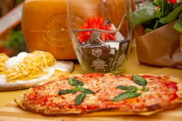 Pyszne rodzaje pizzy, makaron i ser parmezan. W tle szklany wazon z dekoracjami i kwiaty.