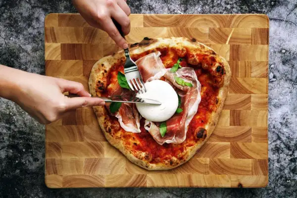 Une pizza burrata avec du prosciutto et du basilic, prête à être dégustée.