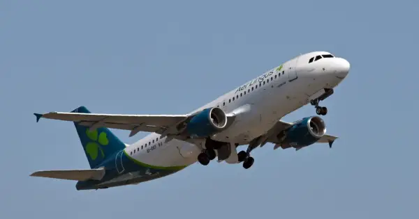 Samolot Aer Lingus z zieloną koniczynką na ogonie wznosi się na błękitne niebo.