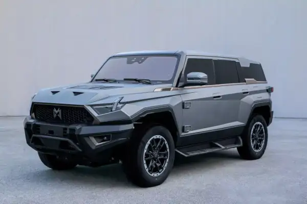 Szary mhero SUV o kanciastym designie, z masywnym grillem i ostrymi liniami.