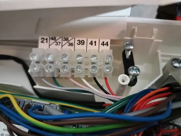 Zaciski elektryczne z numerowanymi wejściami i wiązką kolorowych przewodów.