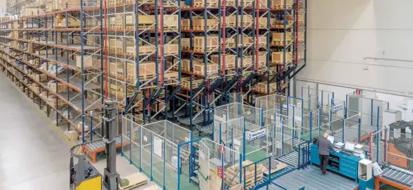 Wysoki regał magazynowy z paletami i wózek widłowy w nowoczesnym centrum logistycznym.