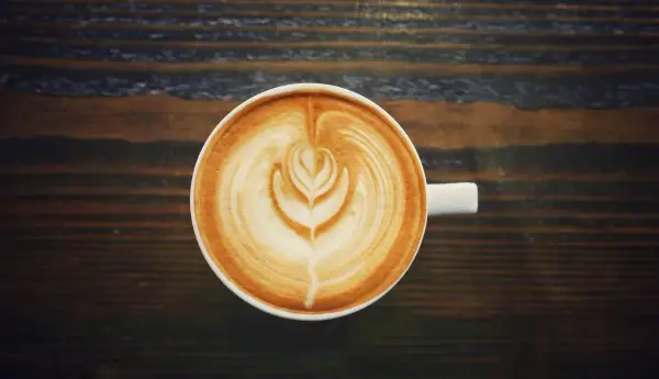 A filiżanka kawy latte z pięknym wzorem na piance. Czy kawa podnosi ciśnienie? Ta pyszna kawa na pewno podniesie Ci nastrój!