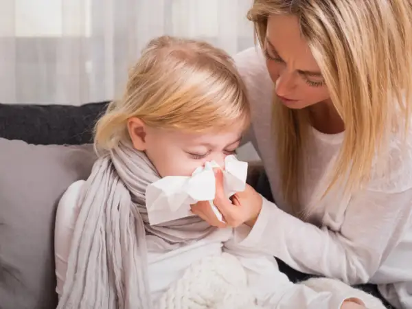 Mama troszczy się o dziecko z zielonym katarem, podając mu chusteczkę.