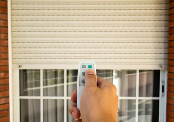 Mano che usa un telecomando per alzare una tapparella elettrica. Utile per capire quanto costa mettere le tapparelle elettriche.