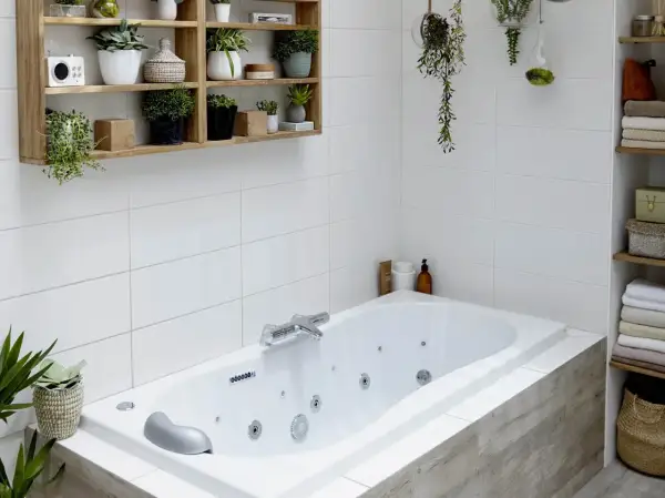 Baignoire d'angle avec robinetterie chromée. La hauteur du robinet baignoire est idéale pour remplir la vasque. Des plantes décorent l'espace.
