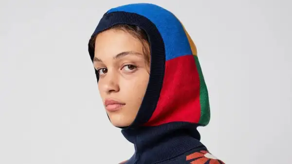 Mujer con balaclava que es una prenda de punto multicolor, con bloques de azul, rojo, amarillo y verde.