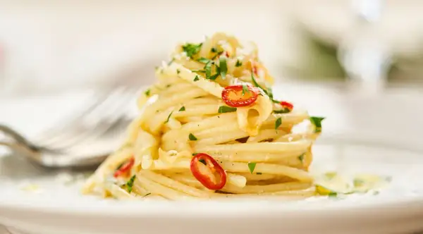 Ein Berg von Spaghetti Aglio e Olio, garniert mit frischer Petersilie und scharfen Chilischeiben.